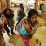 Image: Women carrying children run for safety as armed police hunt gunmen who went on a shooting spree in Westgate shopping centre in Nairobi