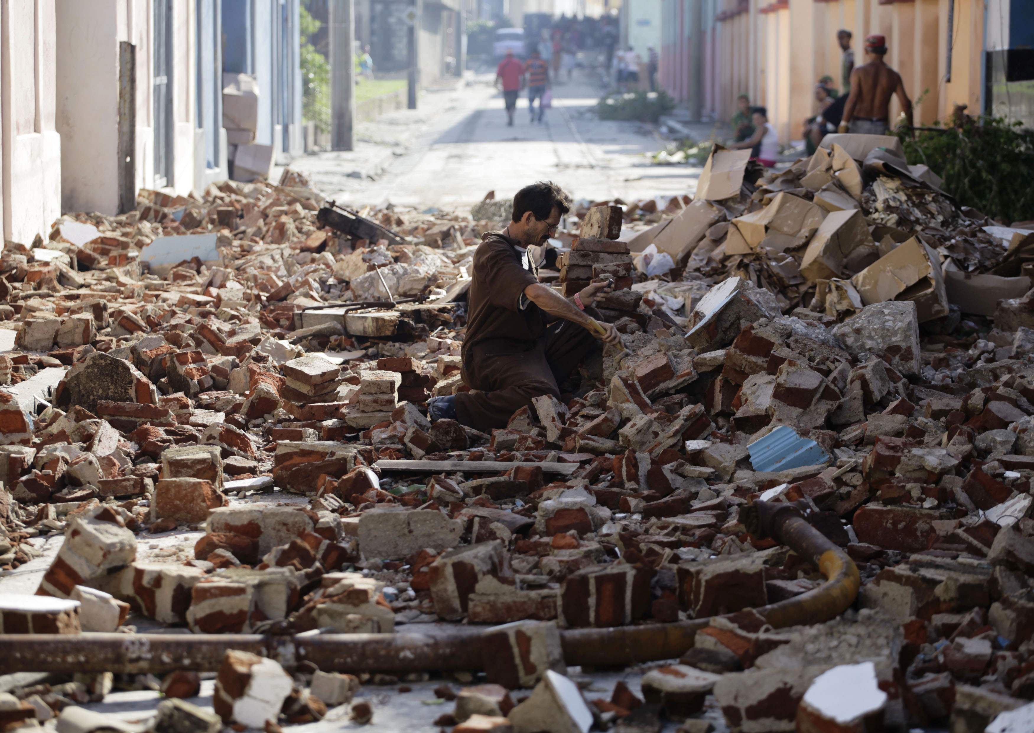 A man salvages bricks from rubble on a street after hurricane Sandy in Santiago de Cuba