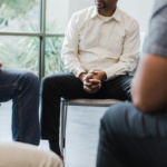 Low angle view men sitting in circle for group therapy